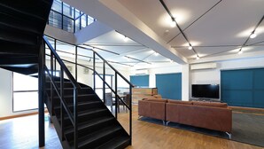 A modern interior with a staircase, a sofa, and a flat-screen TV. - HOTALU Universal Vacation Kan (Osaka)