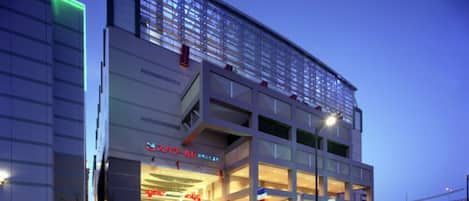 A modern building with a large glass facade, multiple floors, and a prominent entrance with steps.
