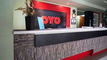 A reception desk with a 'OYO' sign, a clock, and a framed certificate on the wall.