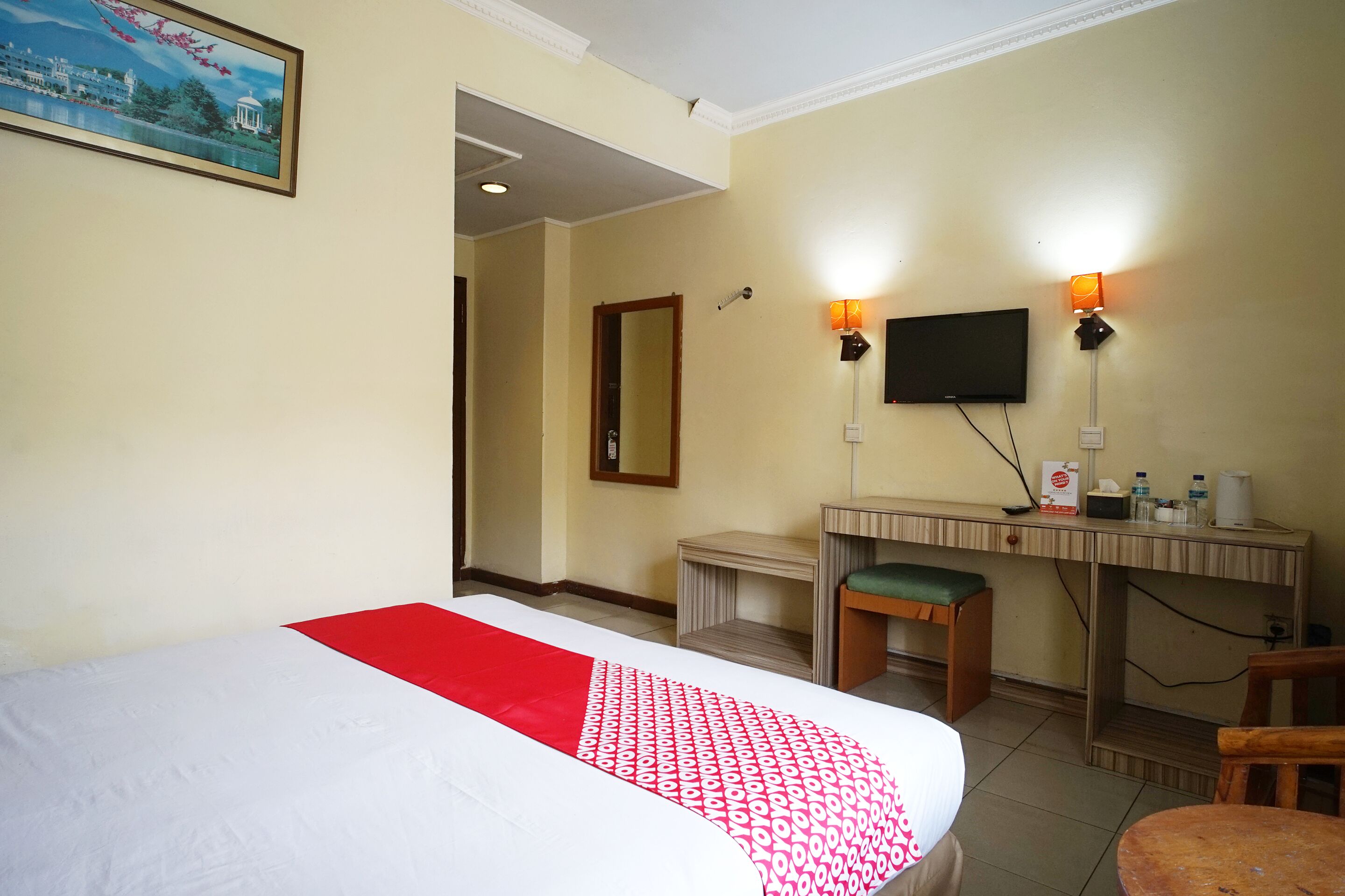 Una habitación de hotel con cama, escritorio, silla y televisor.