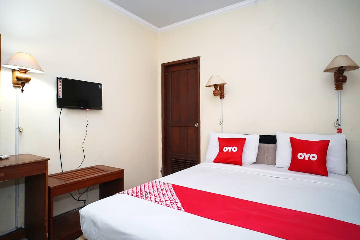 A hotel room with a bed, a desk, a TV, and two lamps.