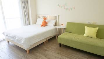 A bedroom with a bed, a green sofa, a small round table, and a wall-mounted decoration.