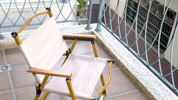 Une chaise pliante sur un balcon carrelé, doté de rampes en métal.