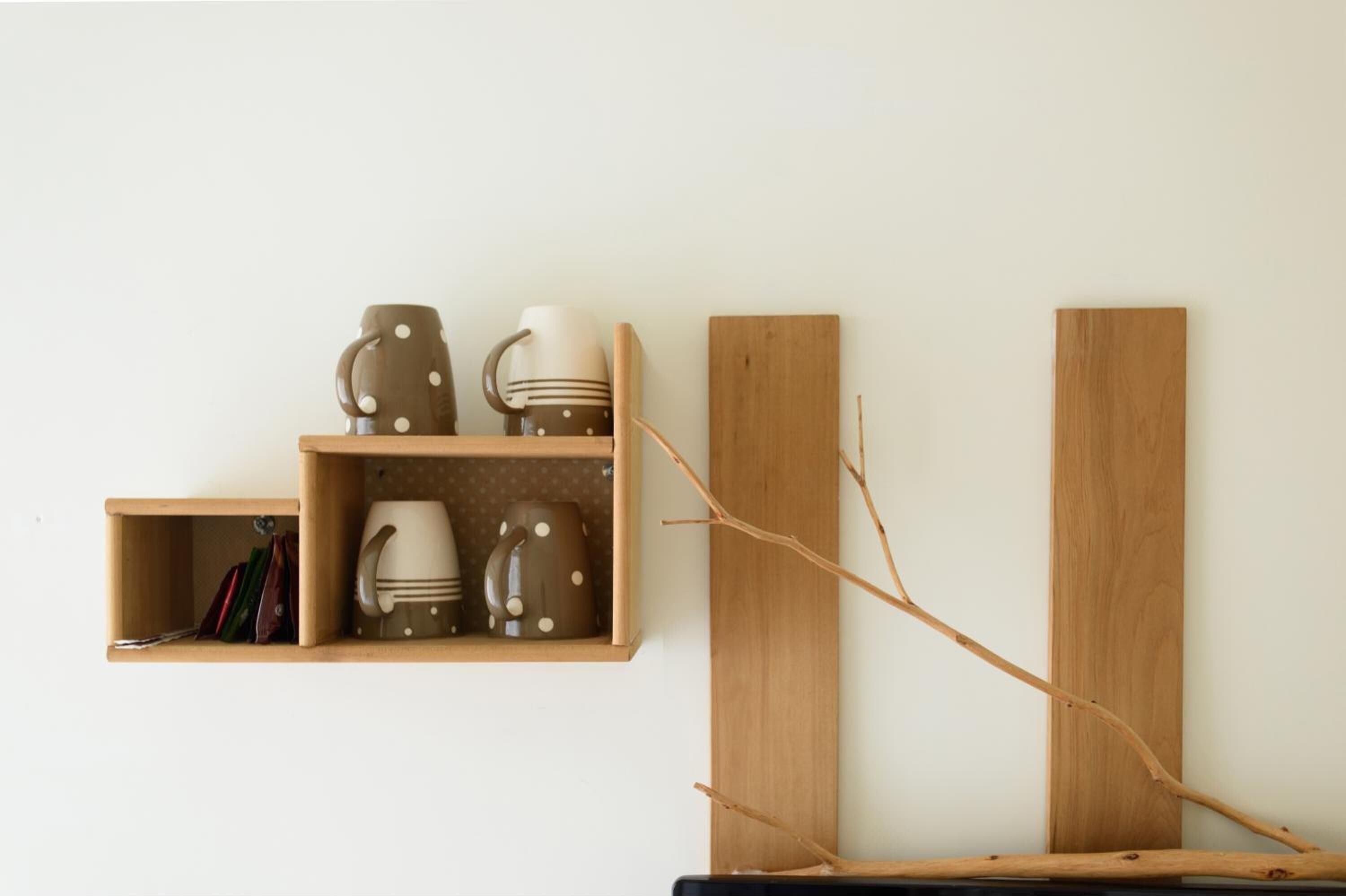Ein Holzboden mit Tassen, Büchern, einem Ast und zwei vertikalen Holzbrettern an einer Wand.