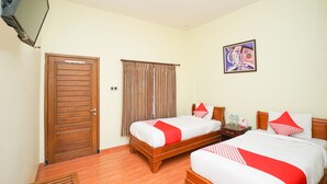 Habitación de hotel con dos camas, una puerta de madera, un televisor montado en la pared y un cuadro.