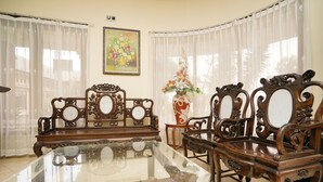 Una habitación tradicional con una mesa de comedor de vidrio, sillas de madera ornamentadas y un arreglo floral.
