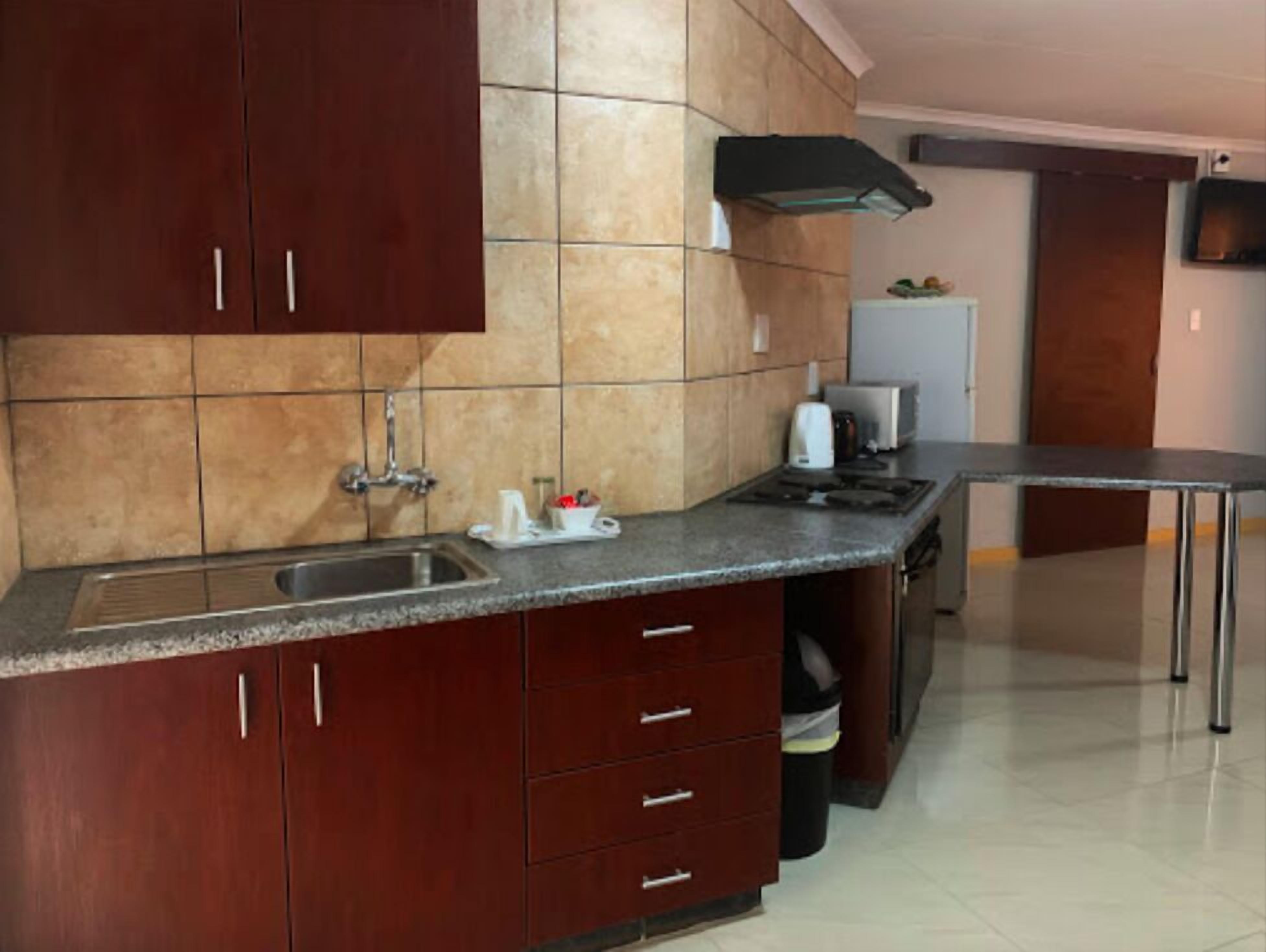Una cocina con armarios de madera oscura, un lavamanos de acero inoxidable y un salpicadero de azulejos.