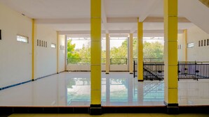 An indoor space with a high ceiling, yellow pillars, and a reflective floor. - Hotel O Family Residence (Kediri)