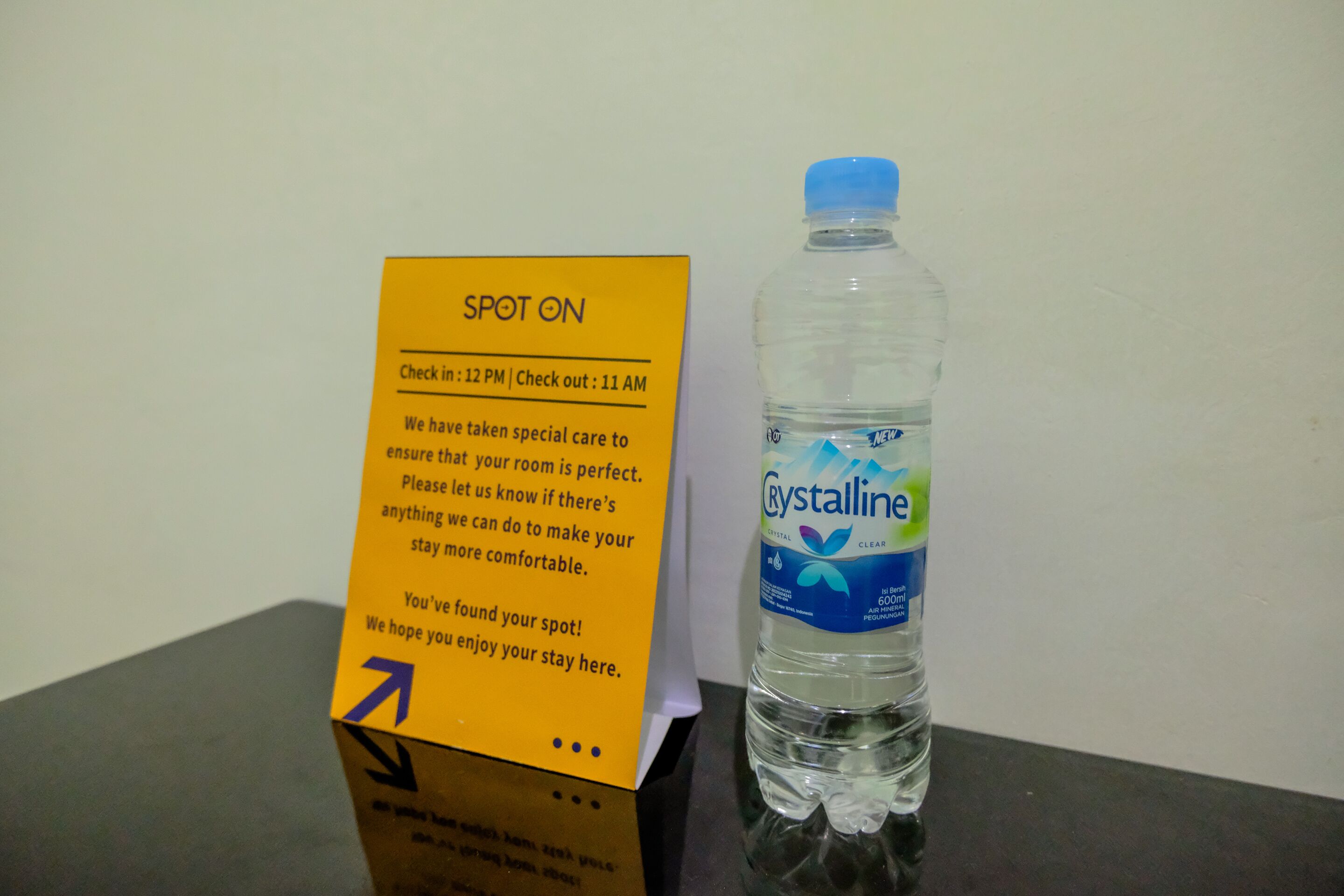 Ein gelbes Schild mit Check-in- und Check-out-Zeiten, eine Wasserflasche und ein Tisch.