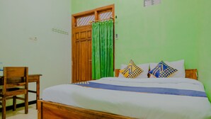 A room with a wooden bed, green walls, a wooden door, and a chair. - Hotel O Family Residence (Kediri)
