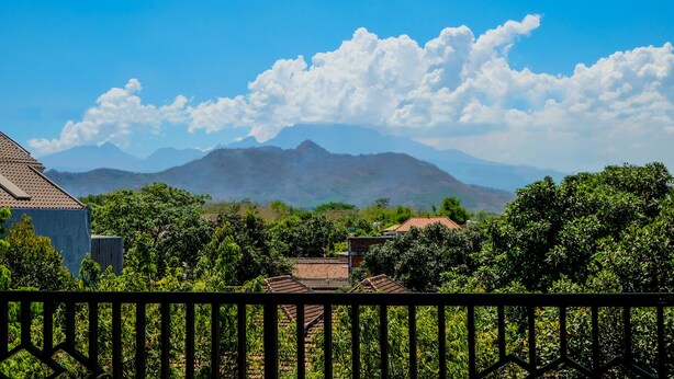A residential area with houses, lush greenery, and mountains in the background. - Hotel O Family Residence (Kediri)