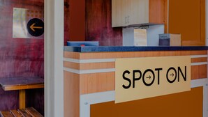 A counter with a sign reading "SPOT ON" and a directional sign with an arrow. - Hotel O Family Residence (Kediri)