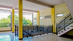 A spacious indoor area with a staircase, metal railings, and a balcony with a view of greenery. - Hotel O Family Residence (Kediri)