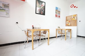Una habitación con dos mesas y sillas de madera, un enchufe en la pared y un cartel con una noria.