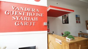 A reception desk with a sign reading "KASIR" and a wall with the text "VANDERA GUEST HOUSE SYARIAH GARUT". - OYO 2021 Wisma Vandera Syariah (Garut)