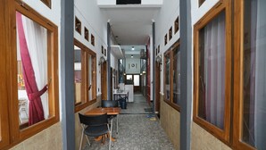 A narrow hallway with a tiled floor, wooden doors, and a table with chairs. - OYO 2021 Wisma Vandera Syariah (Garut)