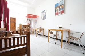 Una habitación amplia con muebles de madera, suelo de baldosas blancas y una pared de acento roja.