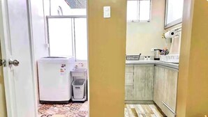 Una cocina con piso estampado, un refrigerador, un bote de basura y gabinetes de madera.