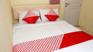 A bed with white and red bedding, two red pillows, and a white door in the background. - OYO 1335 Anie 71 Residence (Bengkulu)