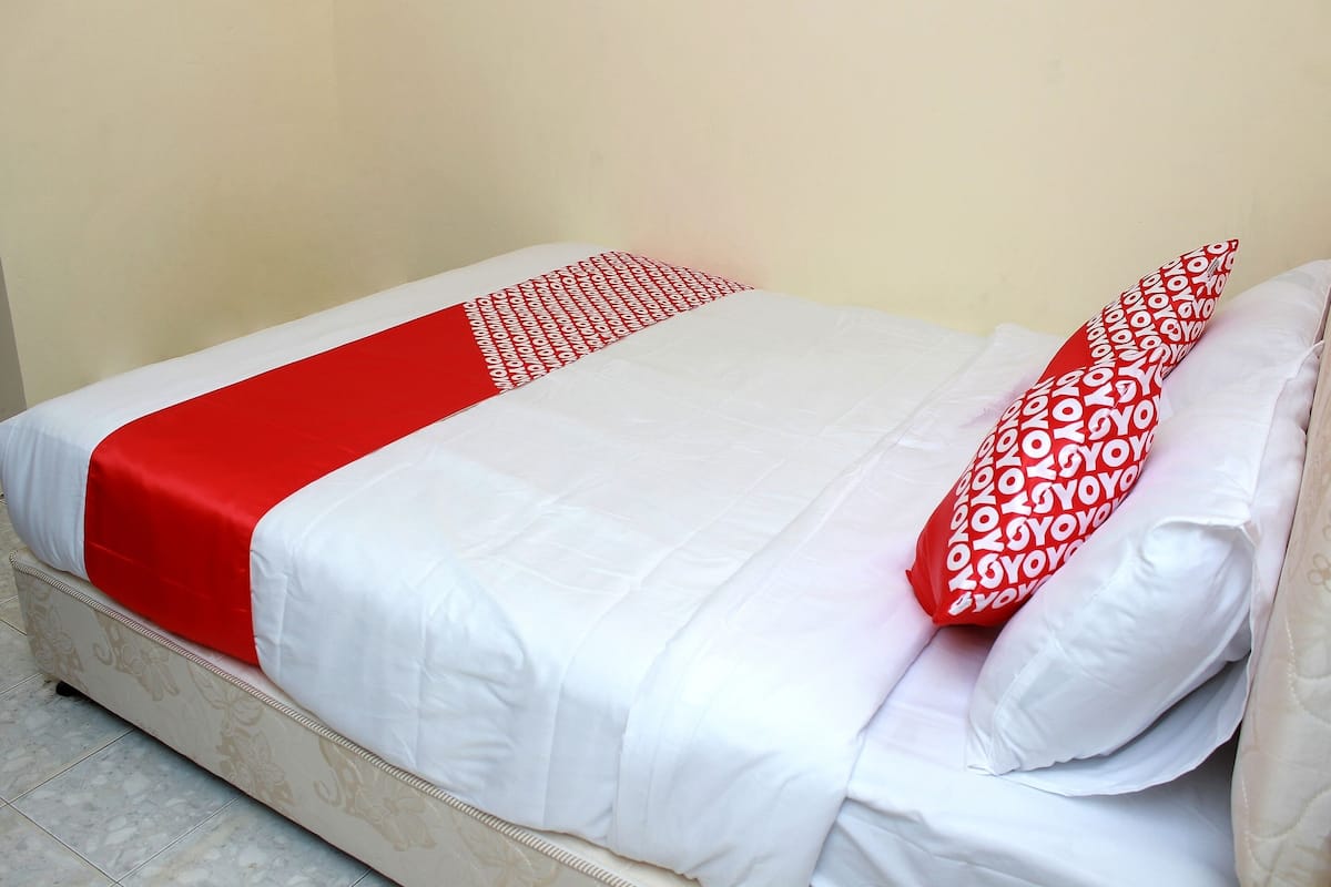 Un lit avec une couvre-lit rouge et blanche et des oreillers assortis.