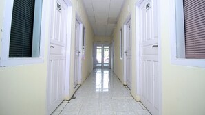 A hallway with doors numbered 05 and 06, leading to a bright room with a door at the end. - OYO 1335 Anie 71 Residence (Bengkulu)