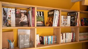 Una estantería con varios libros y revistas, incluyendo títulos como 'Entertainment Weekly' y 'Popeye'.