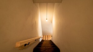 Una escalera estrecha con escalones y barandilla de madera, que lleva a un piso superior.