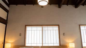A room with a large bed, wooden beams on the ceiling, and two bedside lamps.
