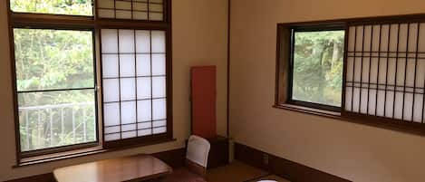 A traditional Japanese room with tatami flooring, a low wooden table, a futon bed, and shoji screens.