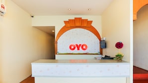 A reception desk with a sign reading "OYO" and a flower vase.