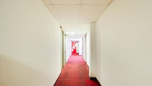A long, narrow hallway with a red carpet and white walls.