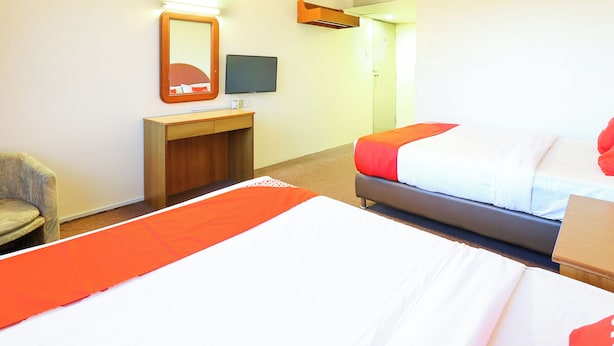 A hotel room with two beds, a desk, a chair, a television, and a door.