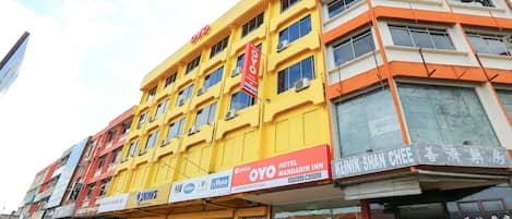 A multi-story building with a yellow facade, featuring a prominent 'OYO' sign and a 'Hotel Mandarin Inn' sign.