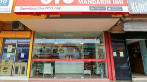 The exterior of the OYO Hotel Mandarin Inn with a prominent red and white signboard, large glass windows, and a visible entrance.