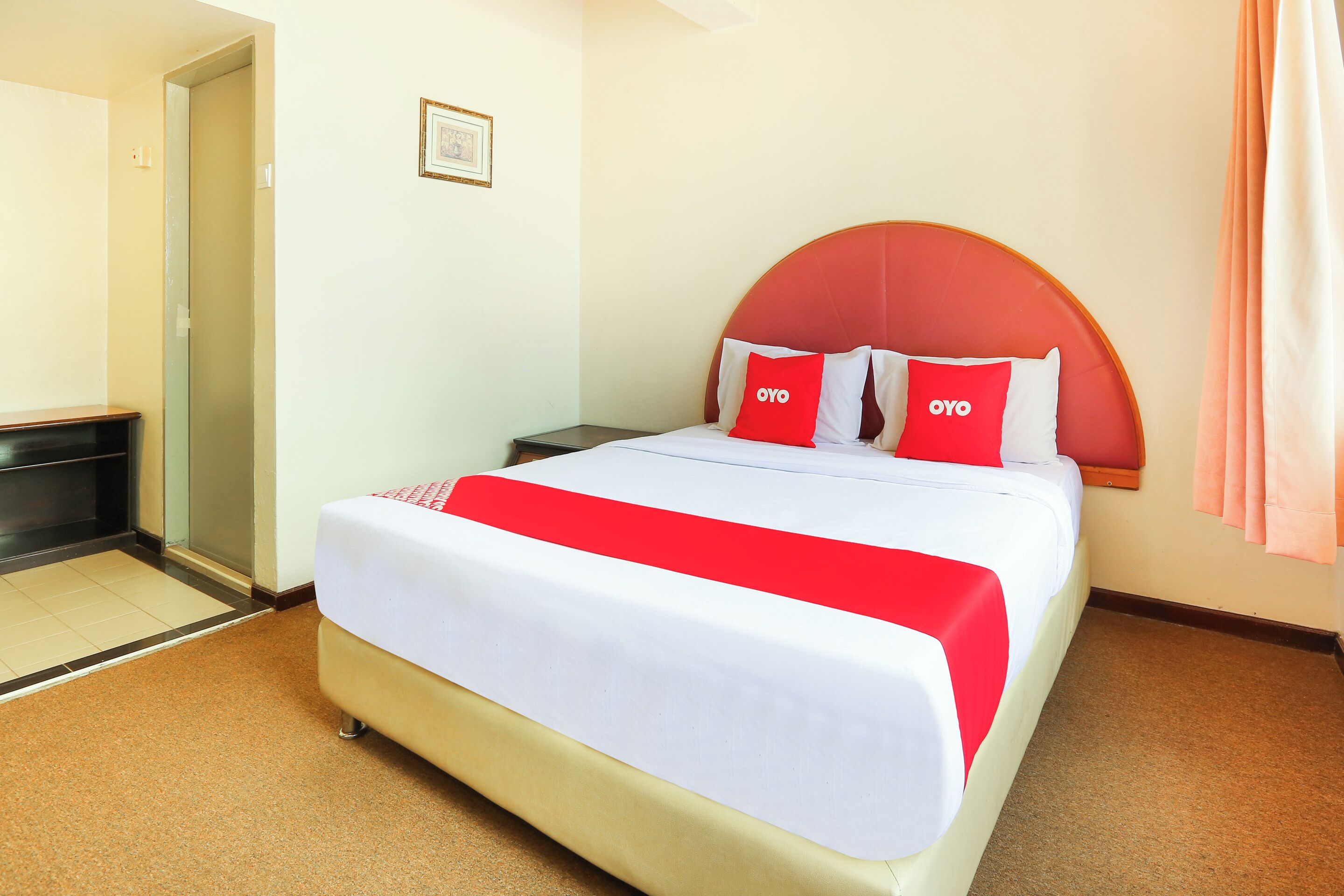 A hotel room with a bed, a nightstand, a chair, and a door.