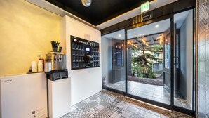 Un hall d’hôtel moderne équipé d’une machine à café, d’un distributeur d’eau et d’un comptoir de réception.