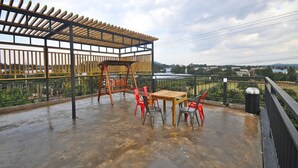 An outdoor patio with a wooden pergola, a table with chairs, and a view of the landscape. - Nonil So Pension (Seogwipo)