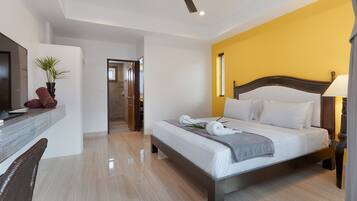 Una habitación de hotel moderna con cama, escritorio, televisor y ventilador de techo.