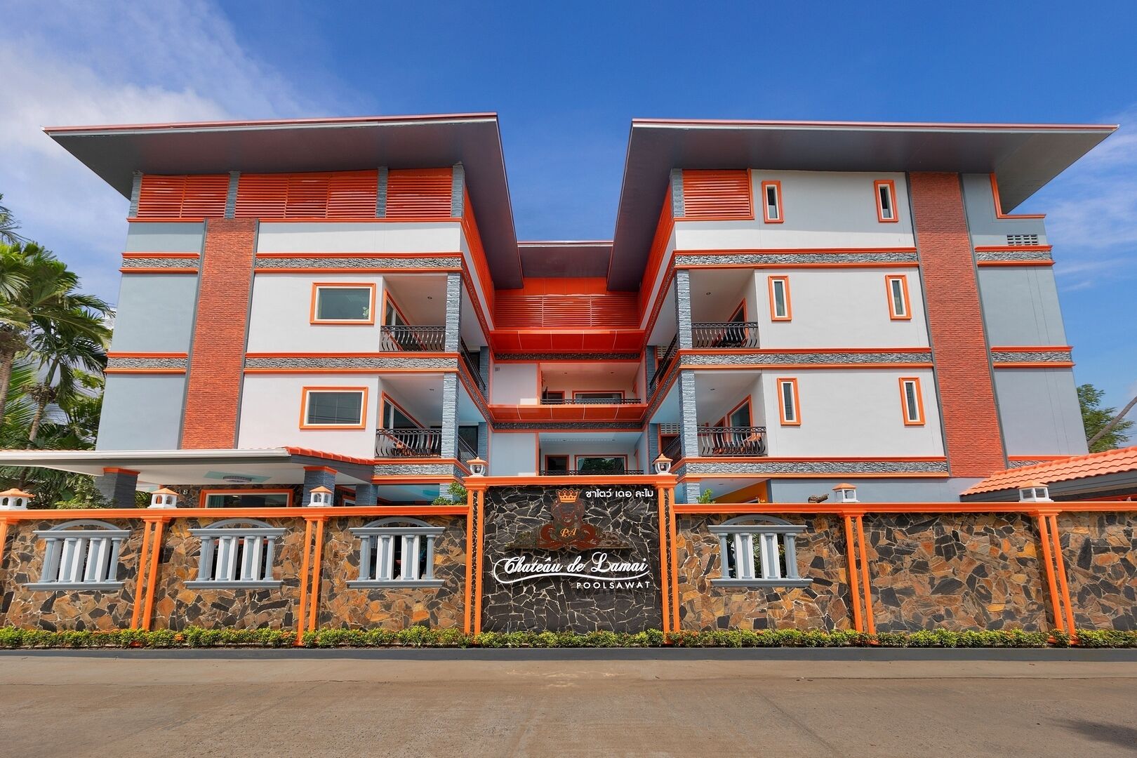 Een modern hotel met een symmetrische gevel, meerdere balkons en een stenen muur met een bord.
