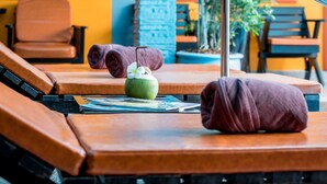 Un espacio de spa con camillas de masaje, una bebida de coco verde y toallas.