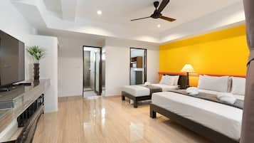 A hotel room with two beds, a TV, a ceiling fan, and a bathroom with a glass door.