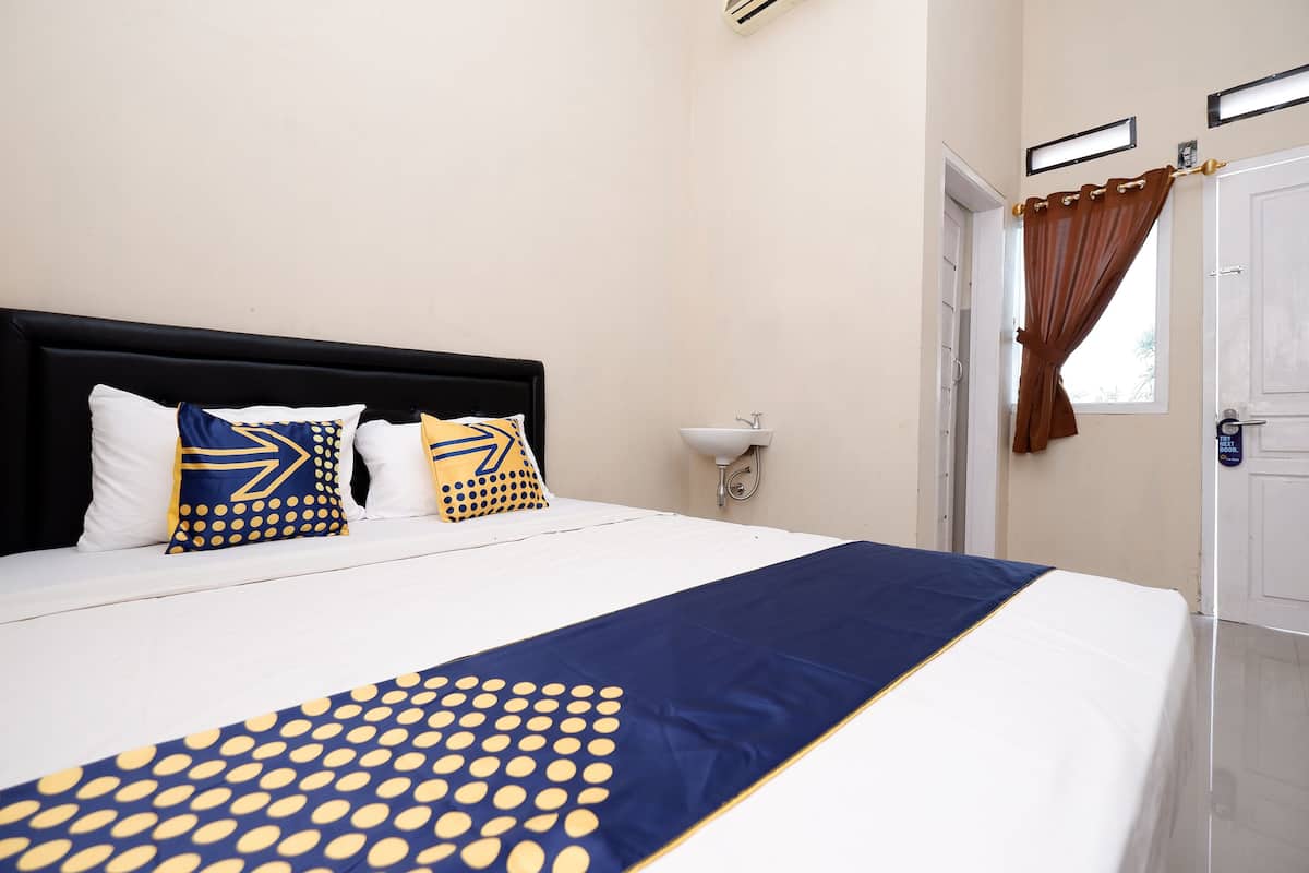 A neatly made bed with a blue and yellow patterned bedspread, white pillows, and a black headboard.