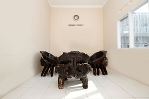 A room with a large, dark, ornate sculpture in the center, a white tiled floor, and a window on the right. - SPOT ON 2027 Putri Guest House Syariah (Cimohong)