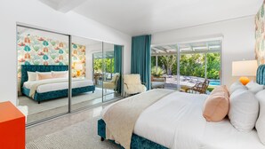 A modern bedroom with a large bed, a glass wall, and a view of an outdoor pool. - Belding Bliss (Palm Springs)