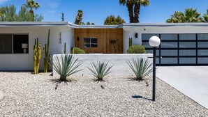 A modern house with a garage, a wooden front door, and a gravel driveway. - Belding Bliss (Palm Springs)