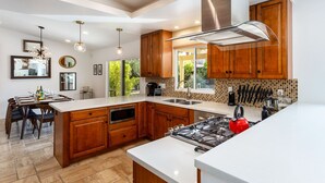 A modern kitchen with wooden cabinets, a large island, and a gas stove. - Modern Loma Vista (Palm Springs)