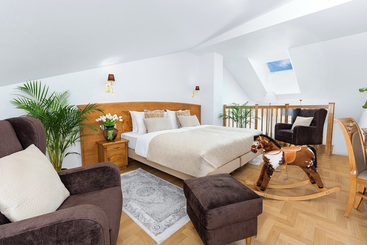 Une chambre moderne avec un lit, un cheval à bascule, un canapé et un coin repas.