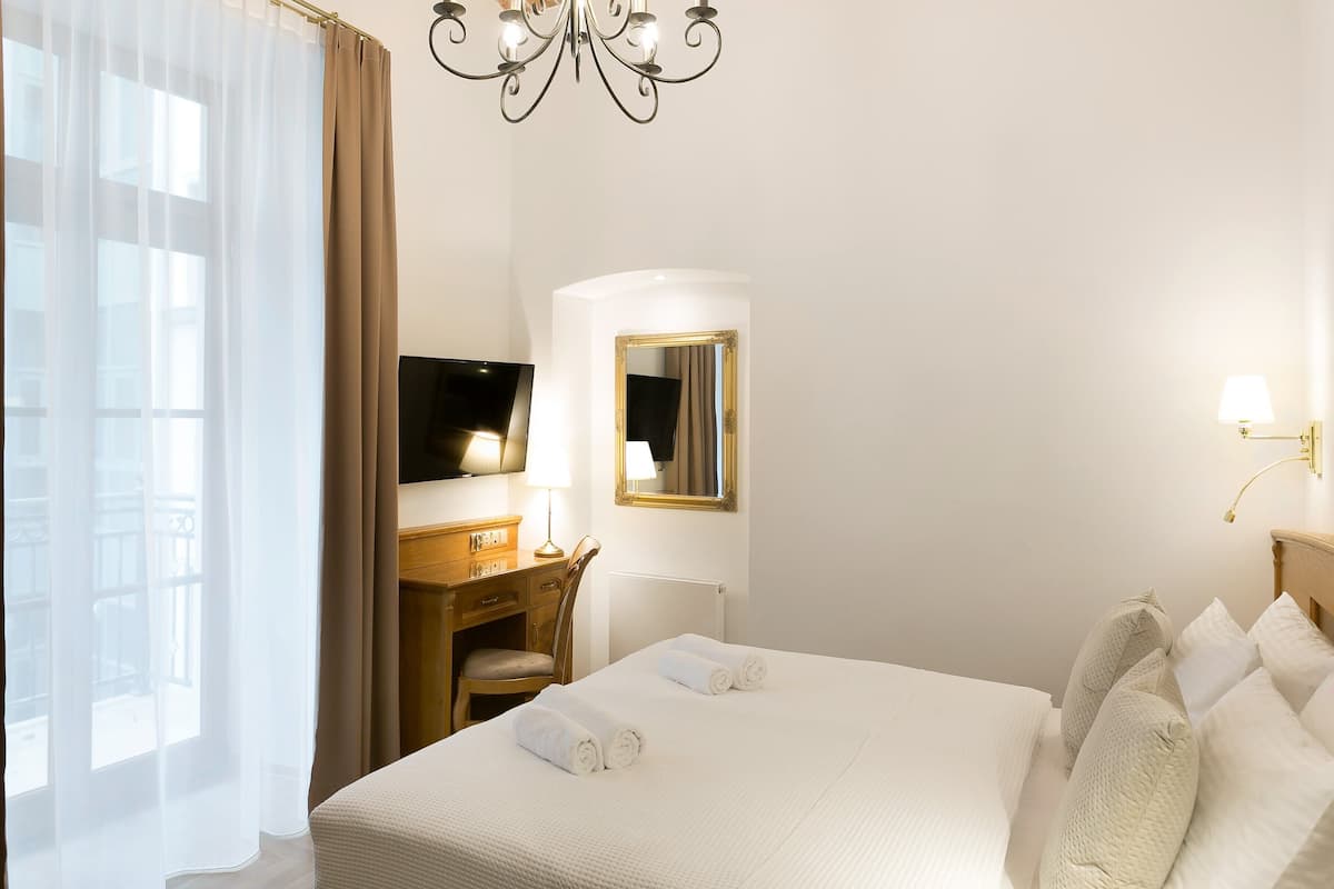 Une chambre d’hôtel équipée d’un lit, d’un bureau, d’une chaise, d’une télévision, d’un miroir et d’un lustre.