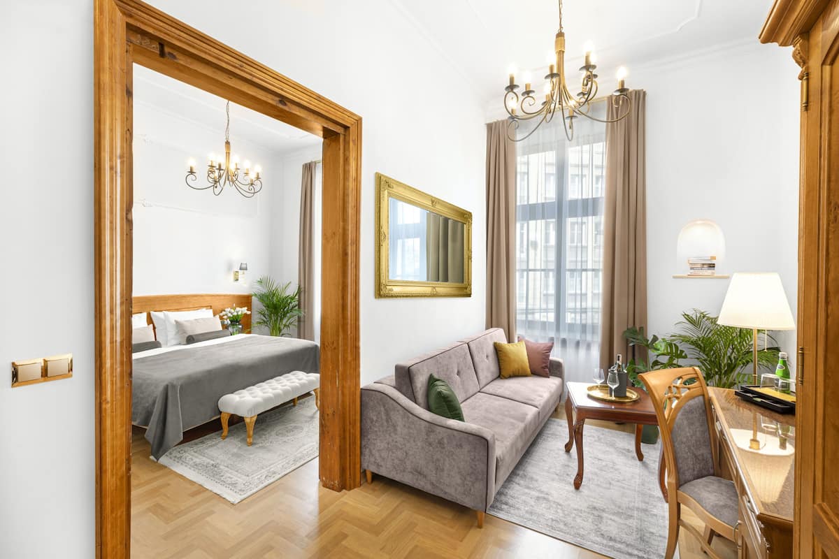 Une chambre d’hôtel comprenant un lit, un canapé, une table à manger et un lustre.