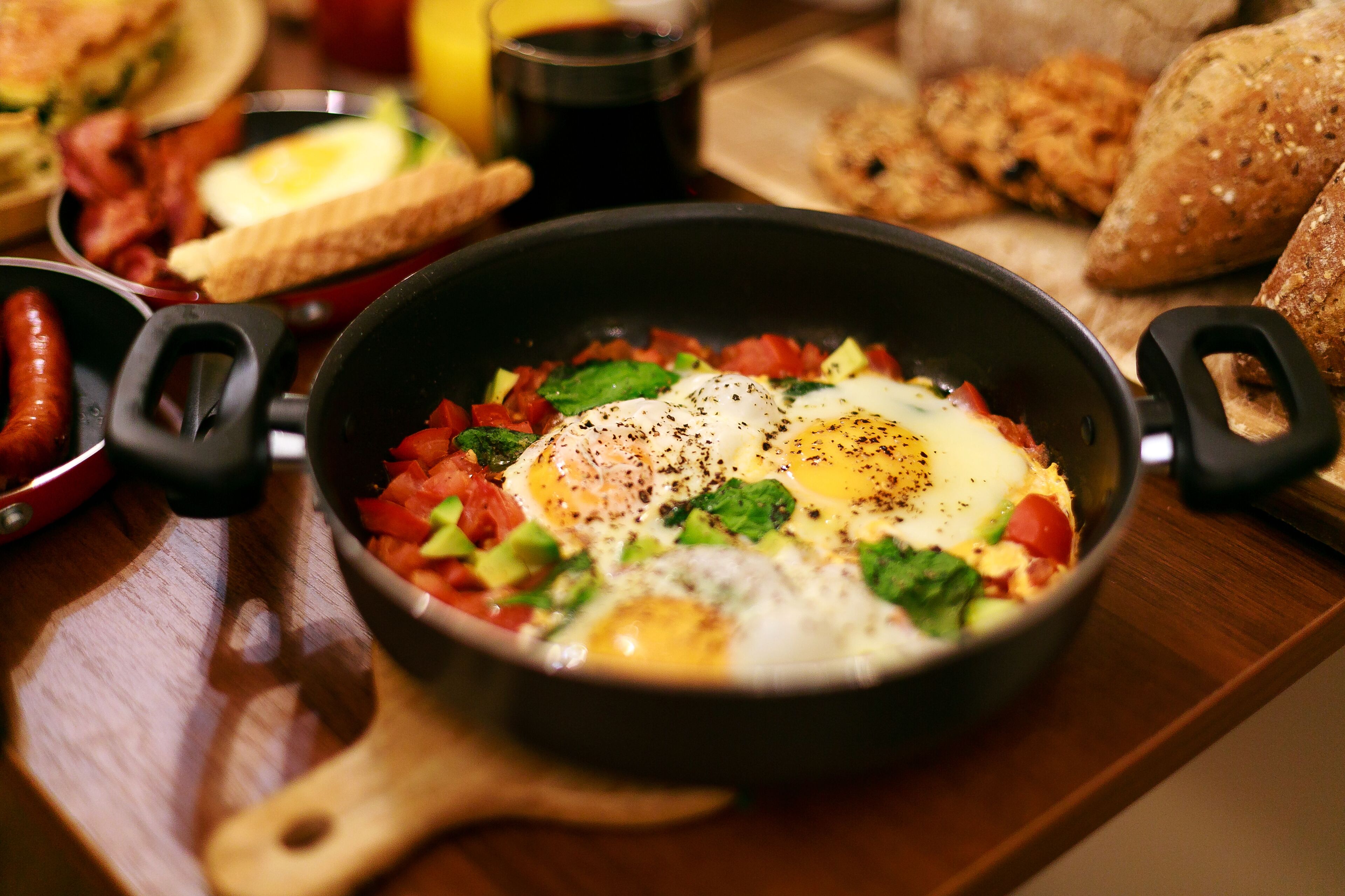 A breakfast dish with eggs, tomatoes, and greens in a pan.